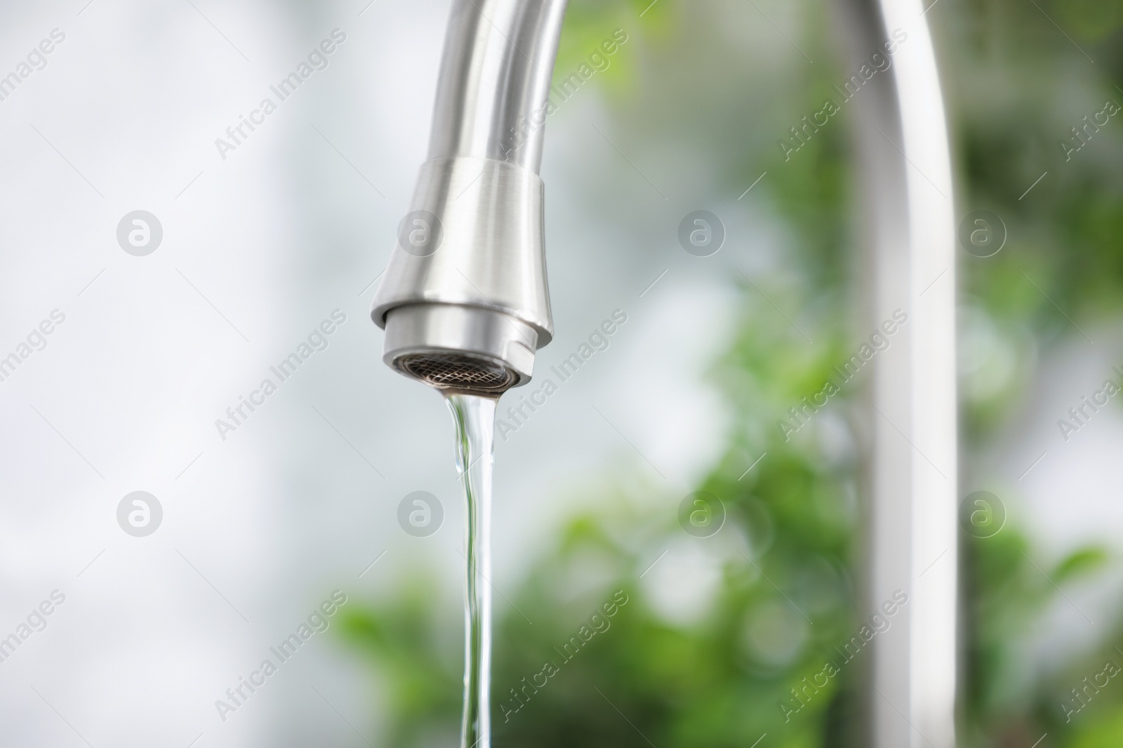 Photo of Water saving concept. Stream of water flowing from tap indoors, closeup