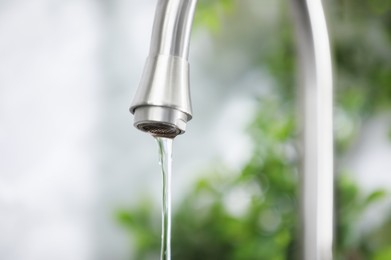Photo of Water saving concept. Stream of water flowing from tap indoors, closeup
