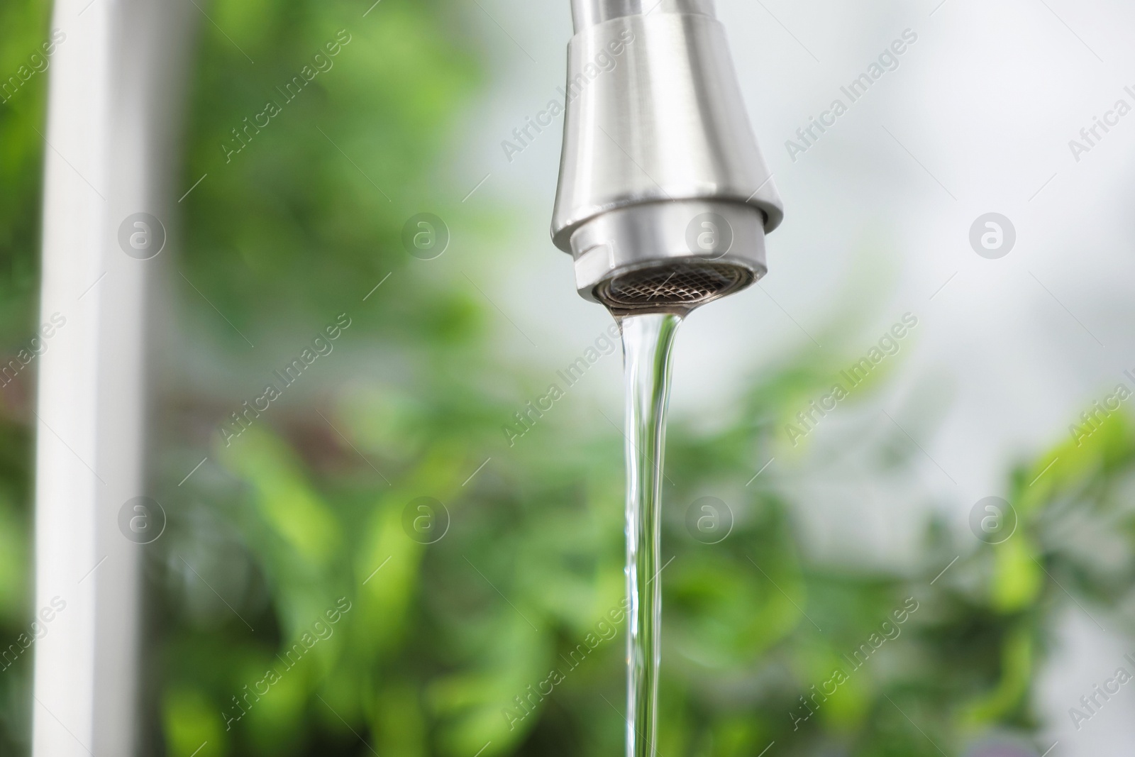 Photo of Water saving concept. Stream of water flowing from tap indoors, closeup