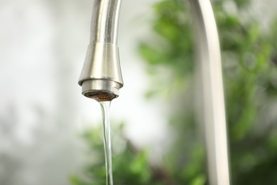 Photo of Water saving concept. Stream of water flowing from tap indoors, closeup. Space for text