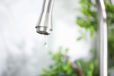 Photo of Save water concept. Water dripping from tap indoors, closeup. Space for text