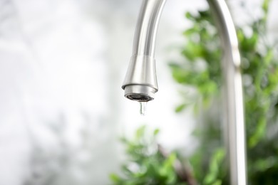 Photo of Save water concept. Water dripping from tap indoors, closeup. Space for text