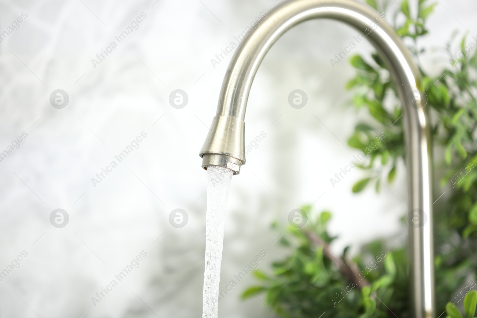 Photo of Water saving concept. Stream of water flowing from tap indoors, closeup