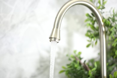 Photo of Water saving concept. Stream of water flowing from tap indoors, closeup