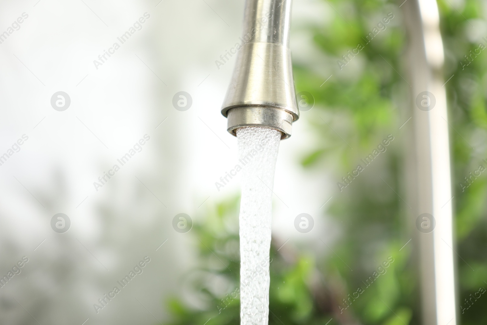 Photo of Water saving concept. Stream of water flowing from tap indoors, closeup