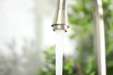 Photo of Water saving concept. Stream of water flowing from tap indoors, closeup