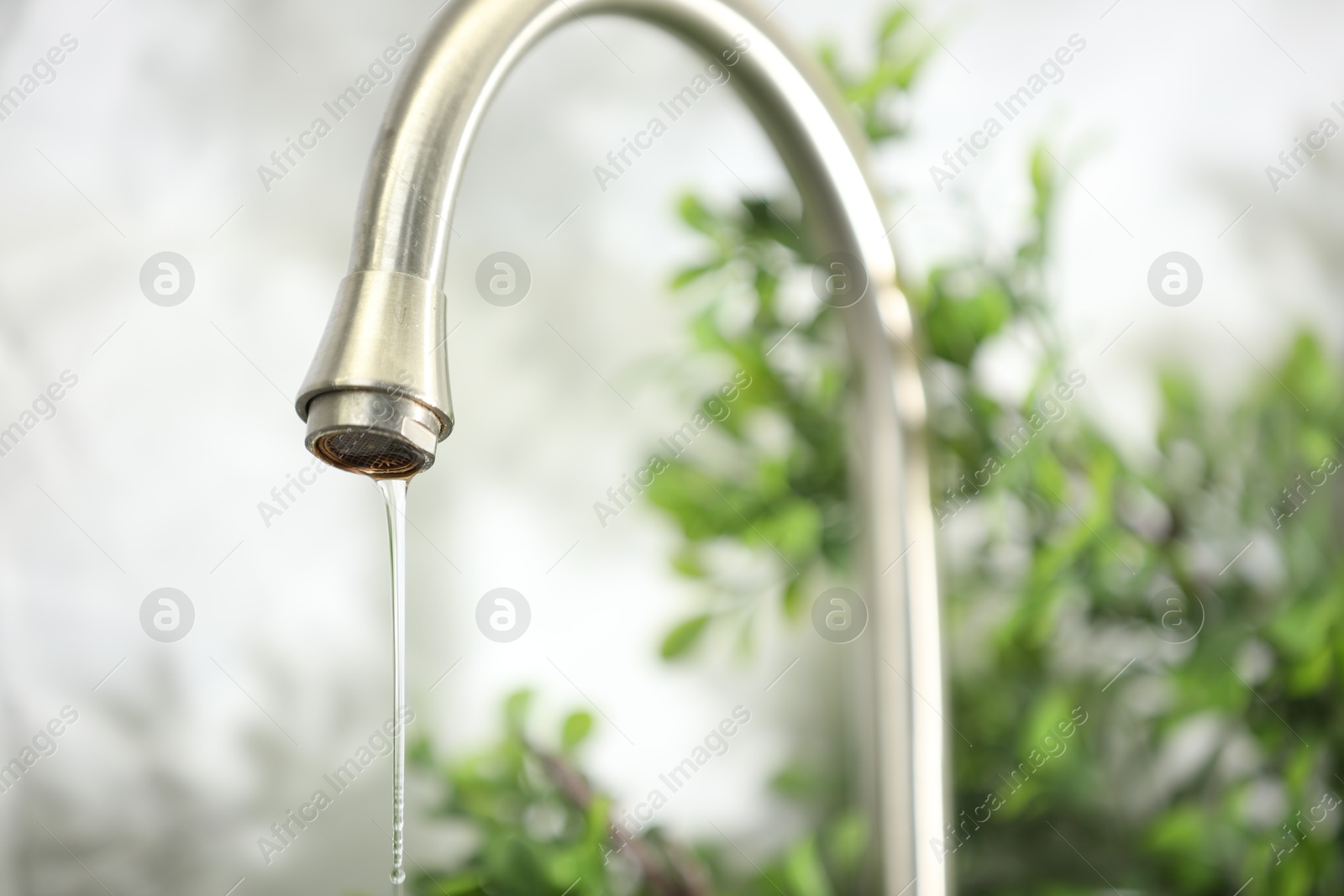 Photo of Save water concept. Water dripping from tap indoors, closeup