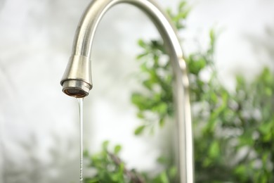 Photo of Save water concept. Water dripping from tap indoors, closeup