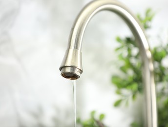 Photo of Save water concept. Water dripping from tap indoors, closeup