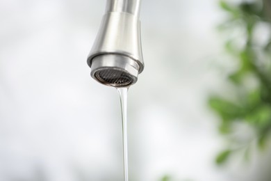 Photo of Save water concept. Water dripping from tap indoors, closeup