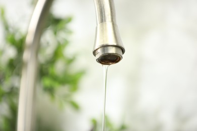 Photo of Save water concept. Water dripping from tap indoors, closeup