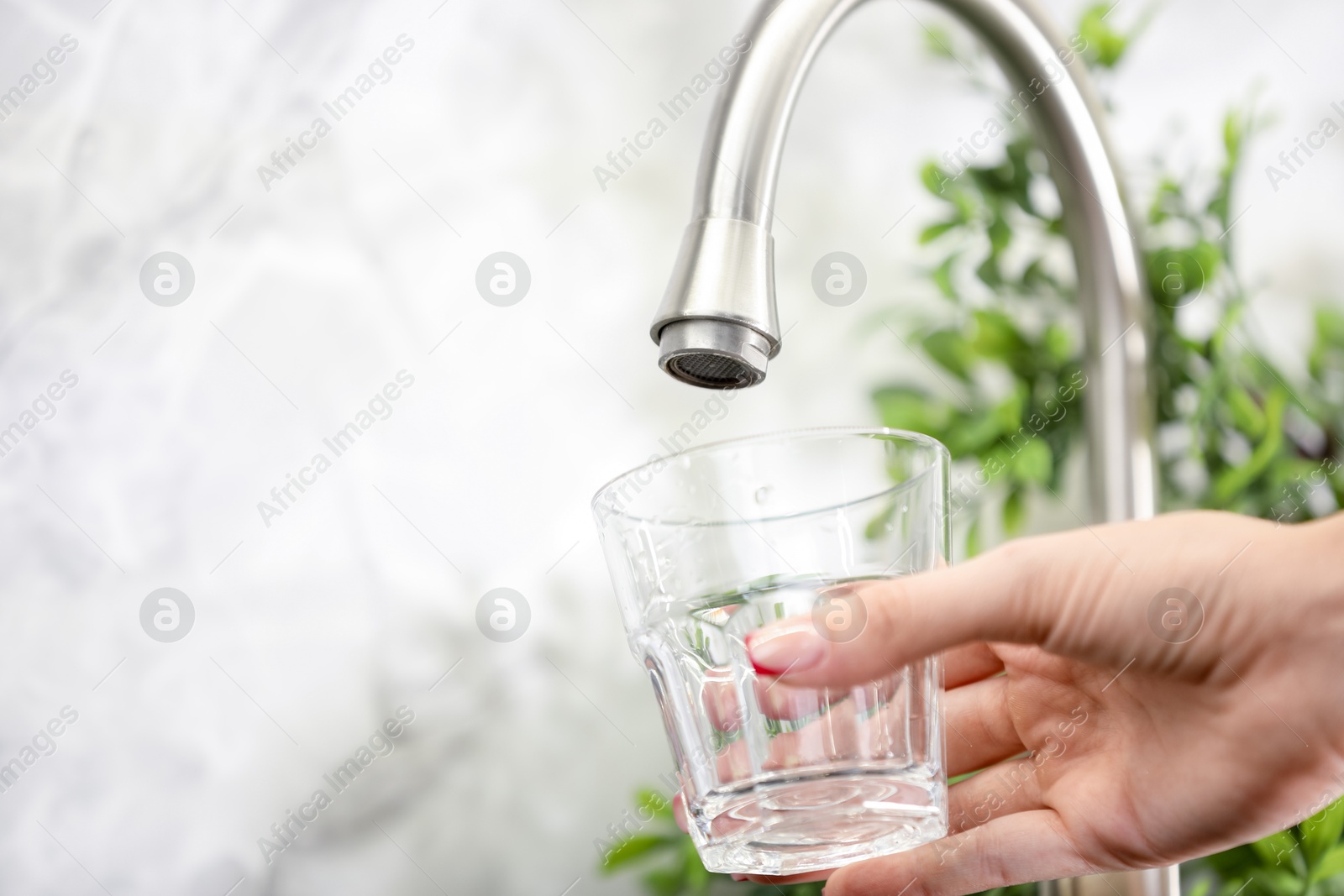 Photo of Water saving concept. Woman filling glass with tap water indoors, closeup. Space for text