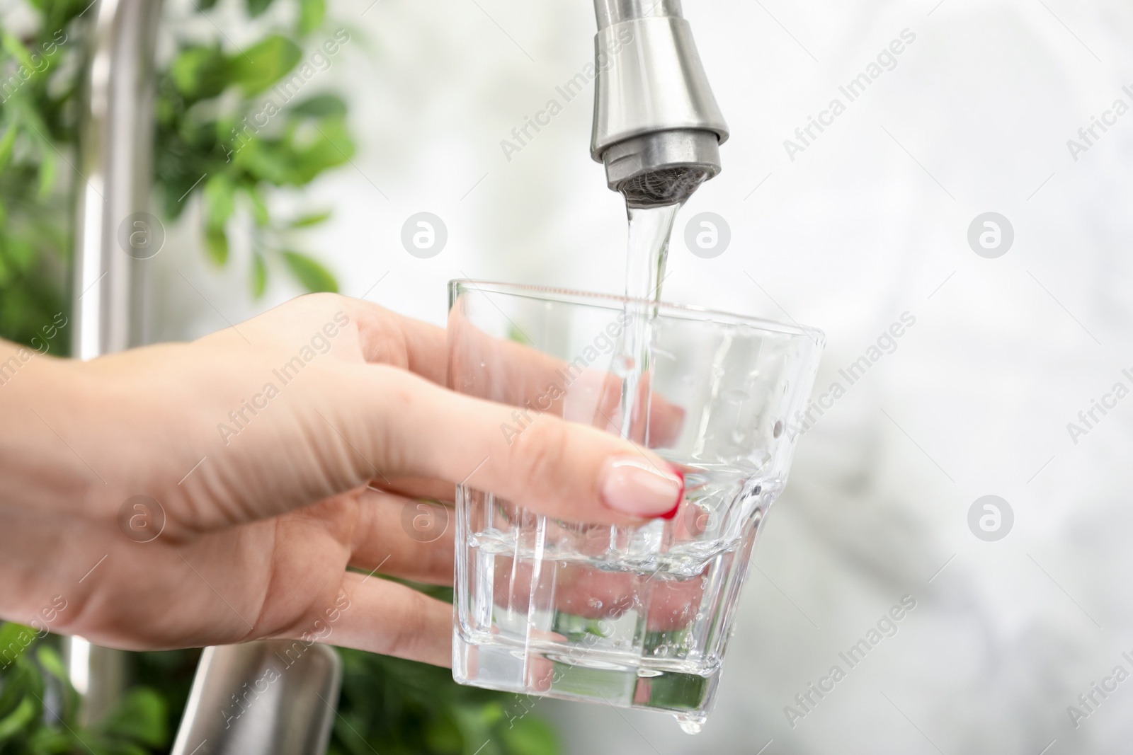 Photo of Water saving concept. Woman filling glass with tap water indoors, closeup