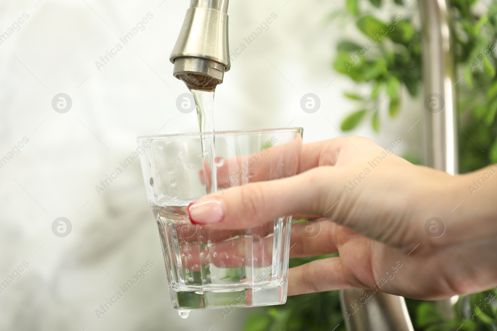Photo of Water saving concept. Woman filling glass with tap water indoors, closeup