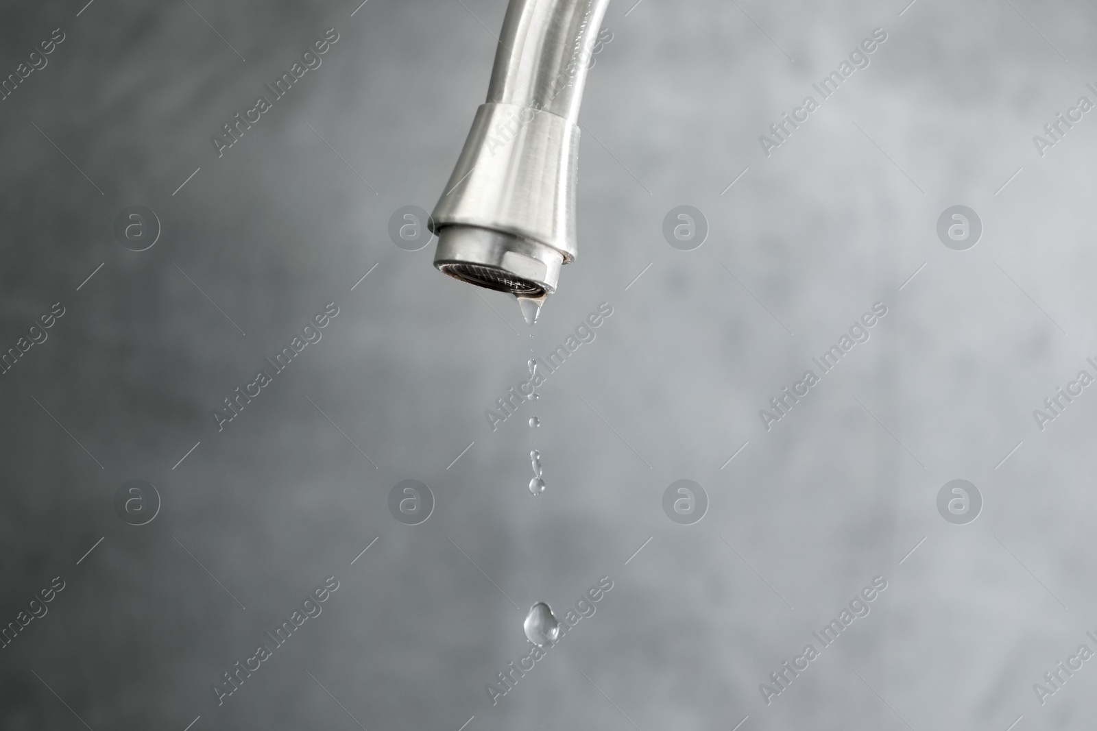 Photo of Save water concept. Water dripping from tap against grey background, closeup