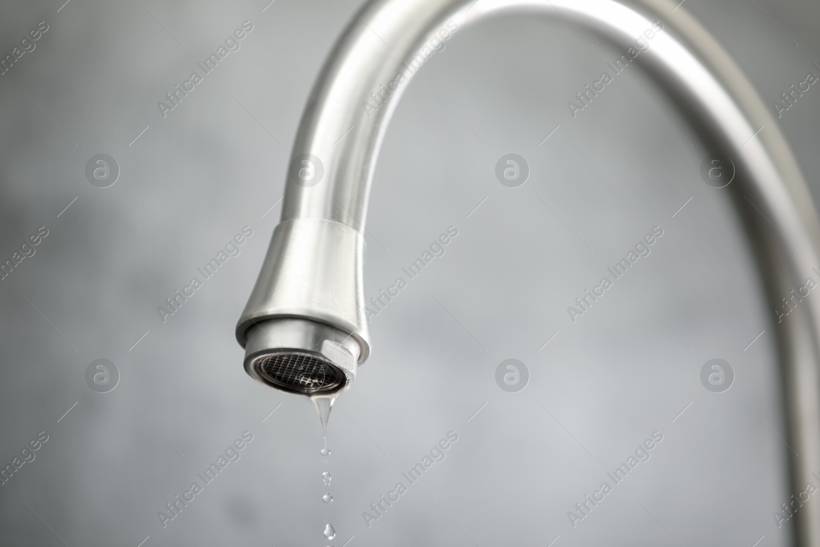 Photo of Save water concept. Water dripping from tap against grey background, closeup