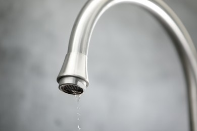 Photo of Save water concept. Water dripping from tap against grey background, closeup