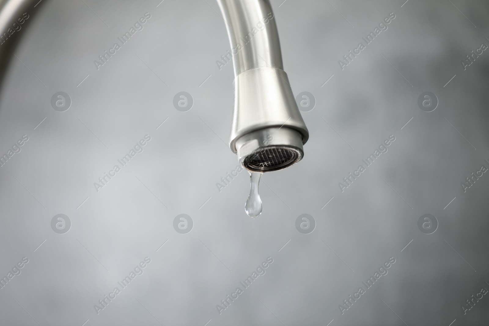 Photo of Save water concept. Water dripping from tap against grey background, closeup