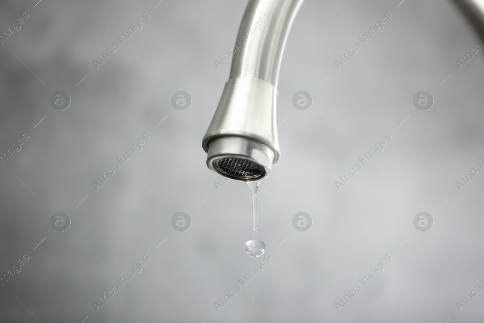 Photo of Save water concept. Water dripping from tap against grey background, closeup