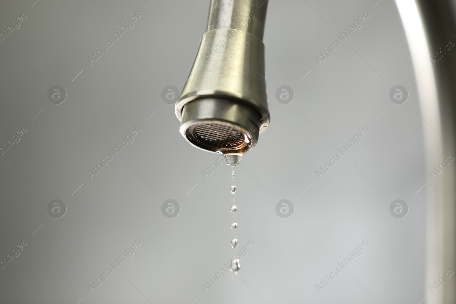 Photo of Save water concept. Water dripping from tap against grey background, closeup