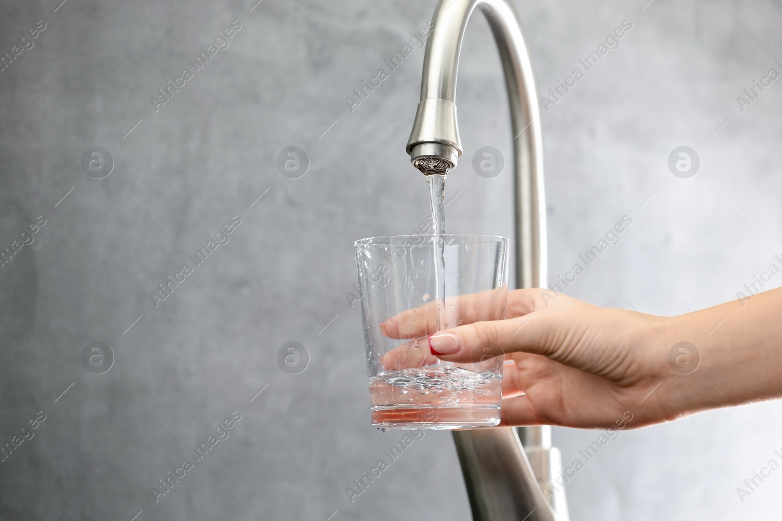 Photo of Water saving concept. Woman filling glass with tap water indoors, closeup. Space for text
