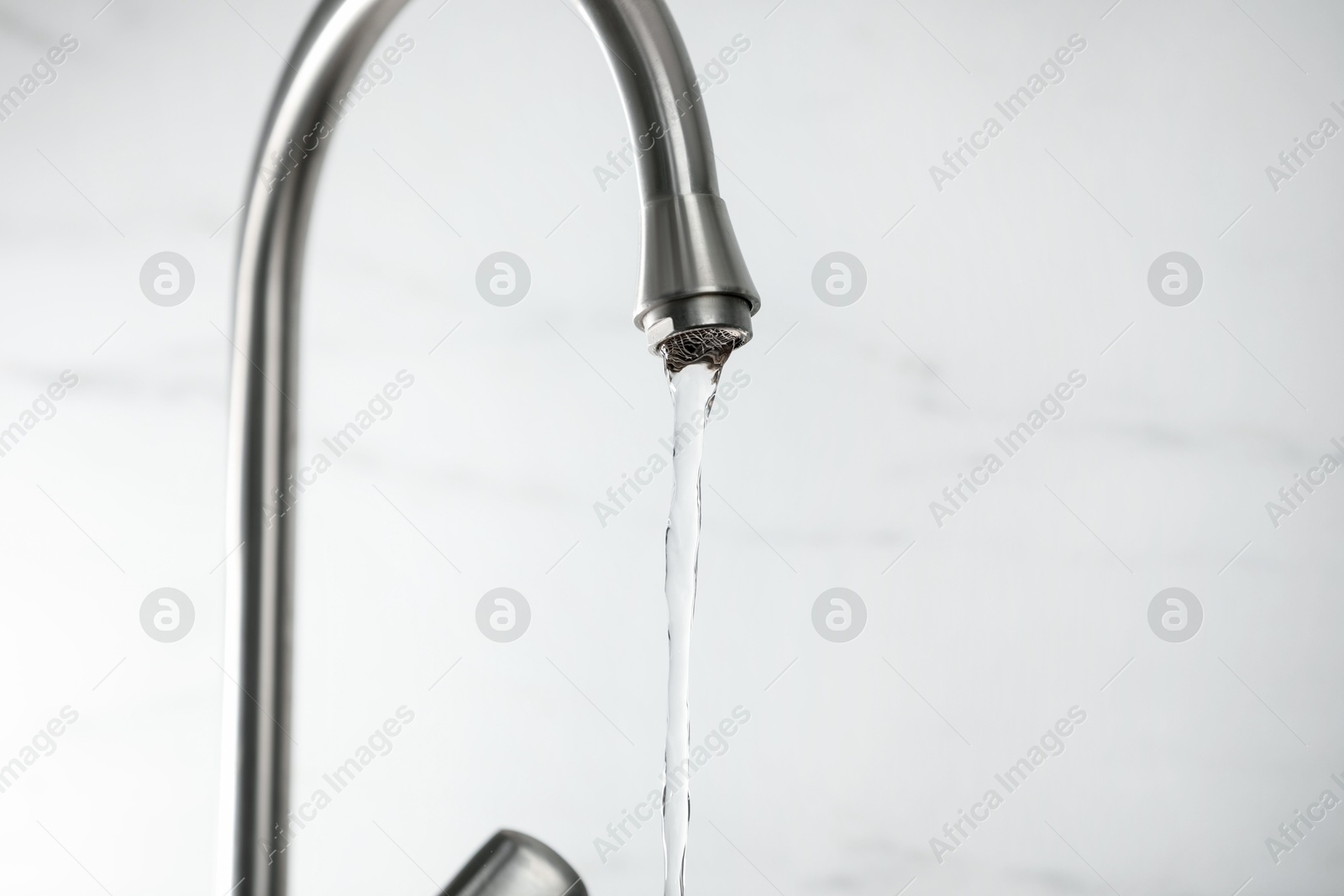 Photo of Save water concept. Stream of water flowing from tap against light background, closeup. Space for text