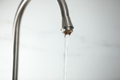 Photo of Save water concept. Stream of water flowing from tap against light background, closeup