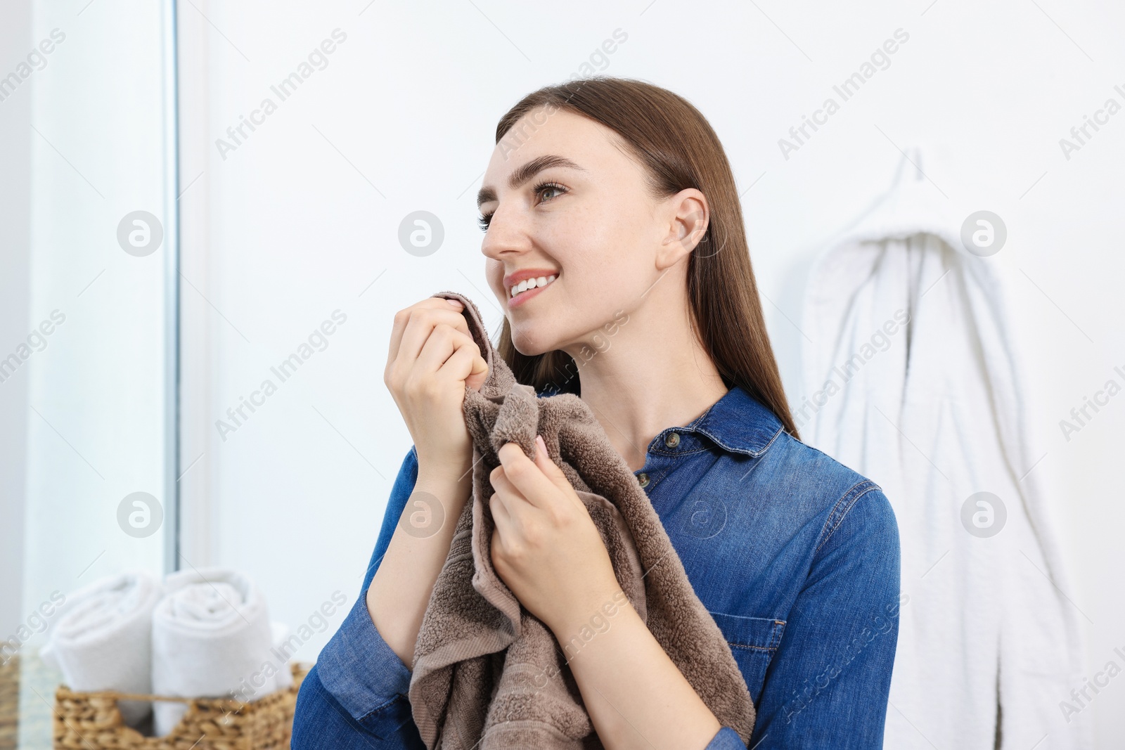 Woman with clean laundry near window indoors Photo of Woman with clean laundry near window indoors