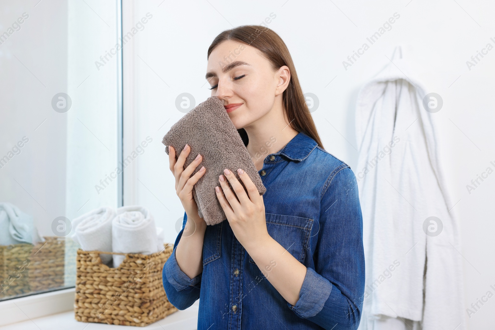 Woman with clean laundry near window indoors Photo of Woman with clean laundry near window indoors