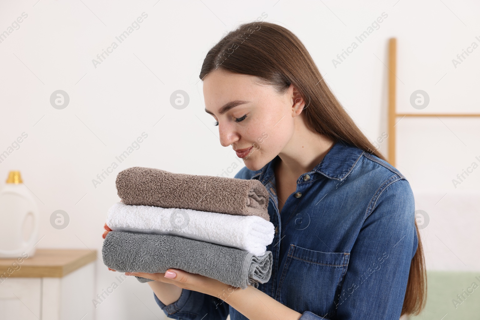Woman with stack of clean laundry indoors Photo of Woman with stack of clean laundry indoors