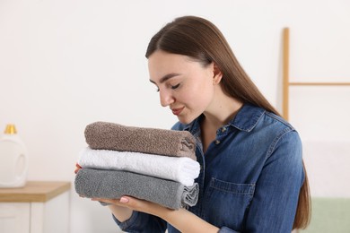 Photo of Woman with stack of clean laundry indoors