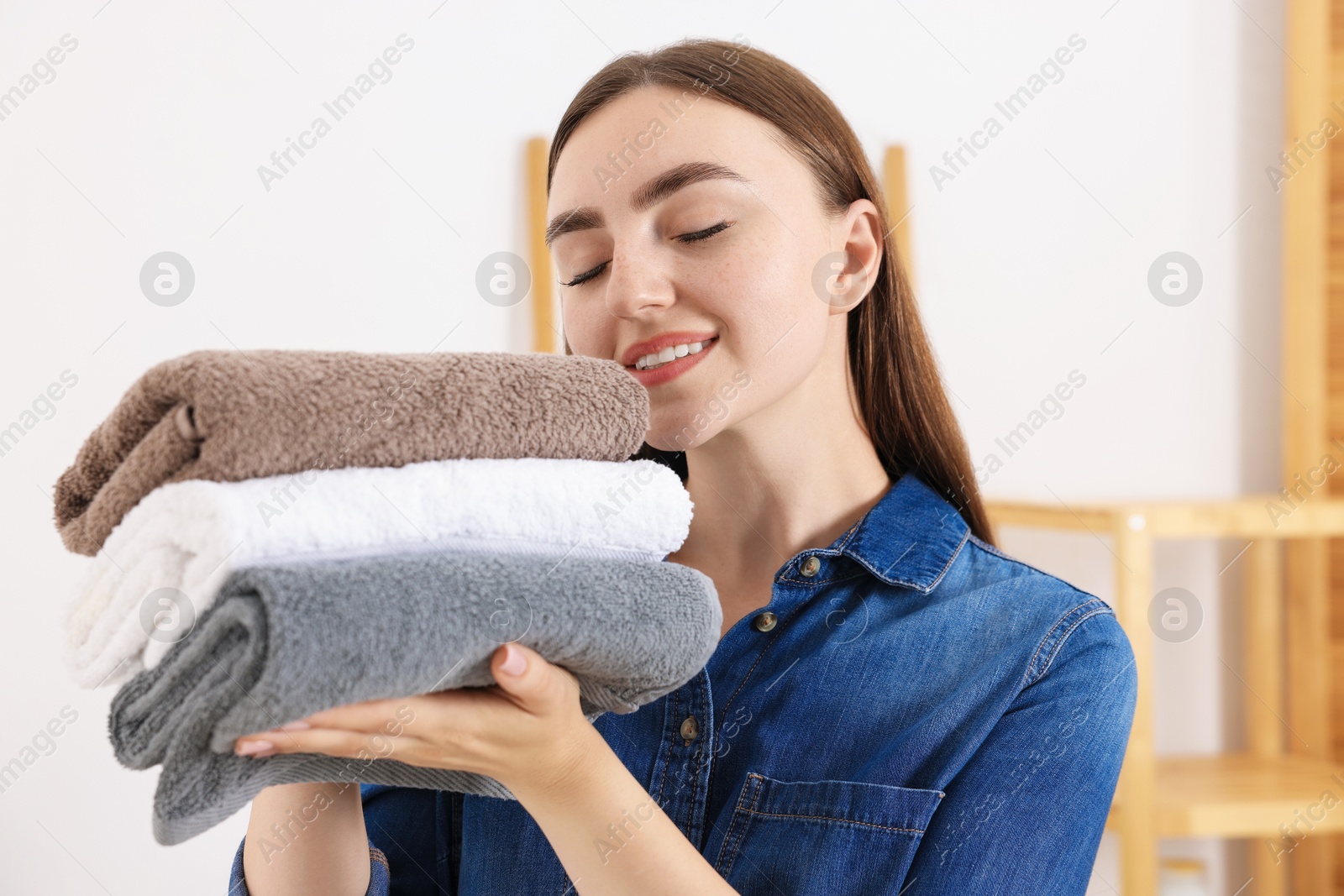 Photo of Woman with stack of clean laundry indoors