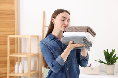 Photo of Woman with stack of clean laundry indoors