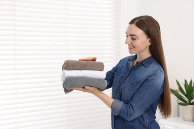 Photo of Woman with stack of clean laundry indoors, space for text