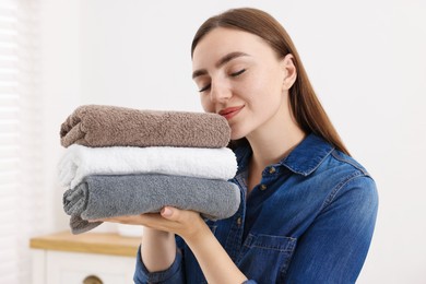 Photo of Woman with stack of clean laundry indoors