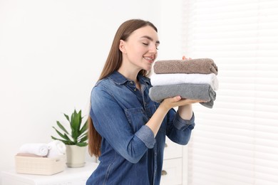 Photo of Woman with stack of clean laundry indoors