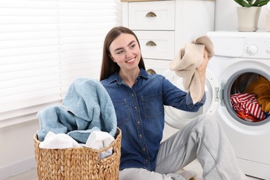 Photo of Woman with laundry near washing machine indoors