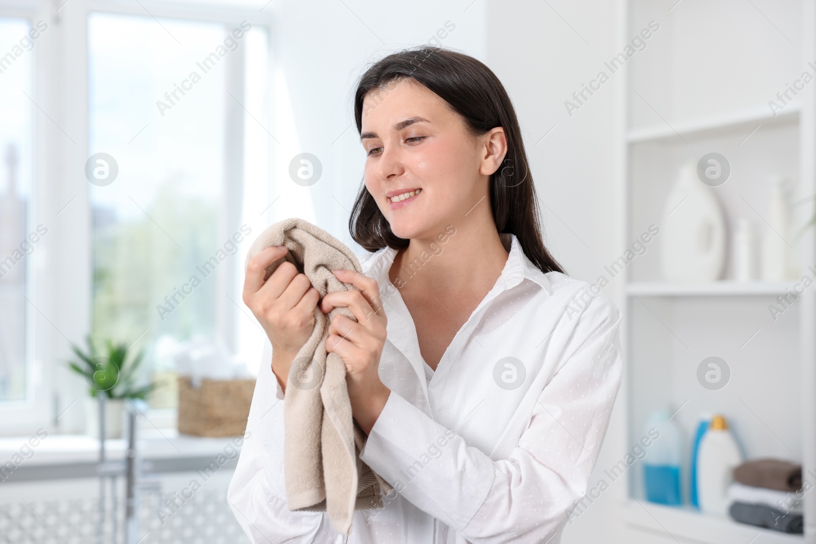 Happy woman with clean laundry at home Photo of Happy woman with clean laundry at home