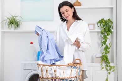Photo of Woman with laundry near washing machine indoors
