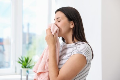 Photo of Woman with clean laundry near window indoors