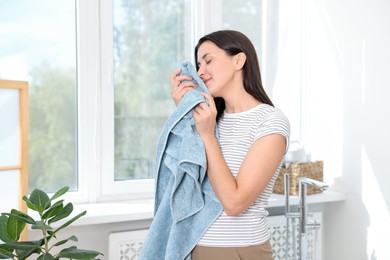 Photo of Woman with clean laundry near window indoors