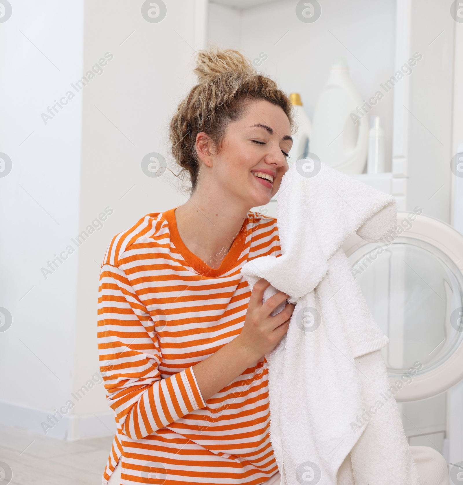 Photo of Woman with laundry near washing machine indoors