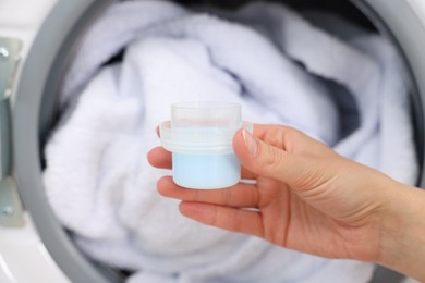 Photo of Woman with detergent near washing machine indoors, closeup. Laundry day