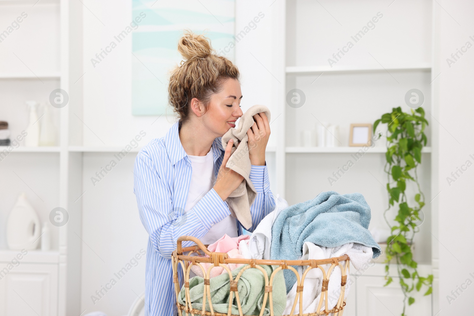 Photo of Woman with basket full of laundry indoors