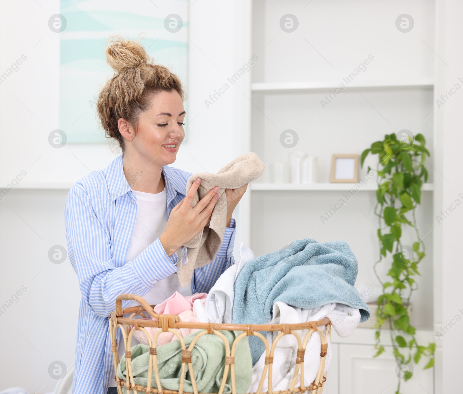 Woman with basket full of laundry indoors Photo of Woman with basket full of laundry indoors