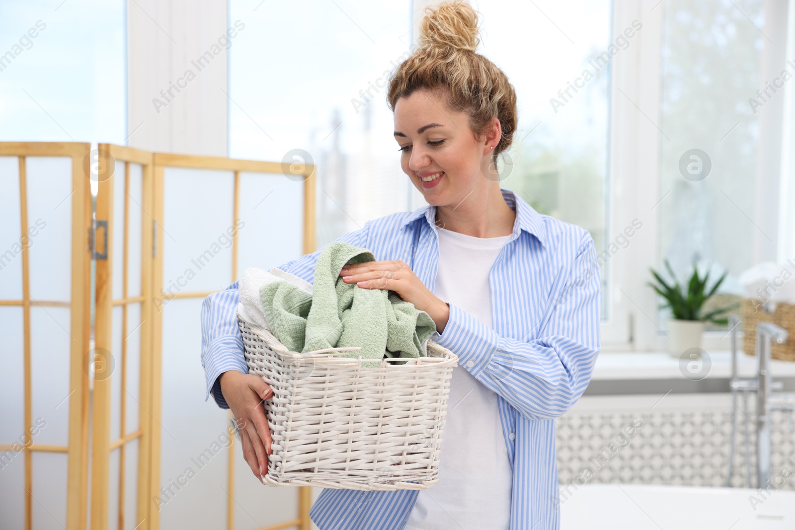 Photo of Woman with basket full of laundry indoors