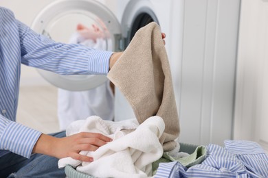 Photo of Woman with laundry near washing machine indoors, closeup