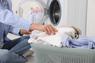 Photo of Woman with laundry near washing machine indoors, closeup