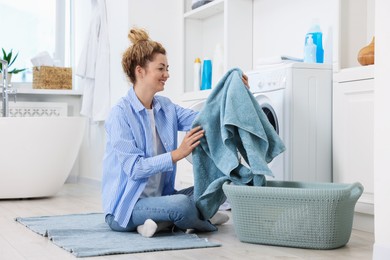 Photo of Woman with laundry near washing machine indoors