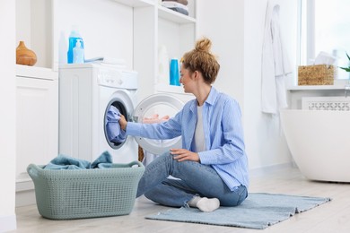 Photo of Woman putting dirty laundry into washing machine indoors